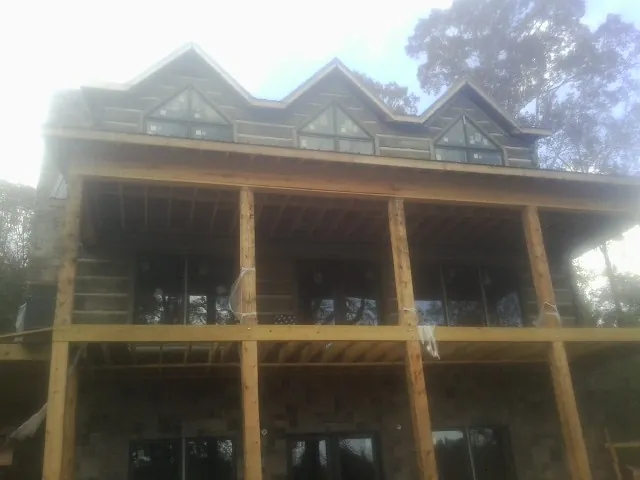 Dormers and porch framing on a large log home under construction — Roof Coating work by our crew in Melrose